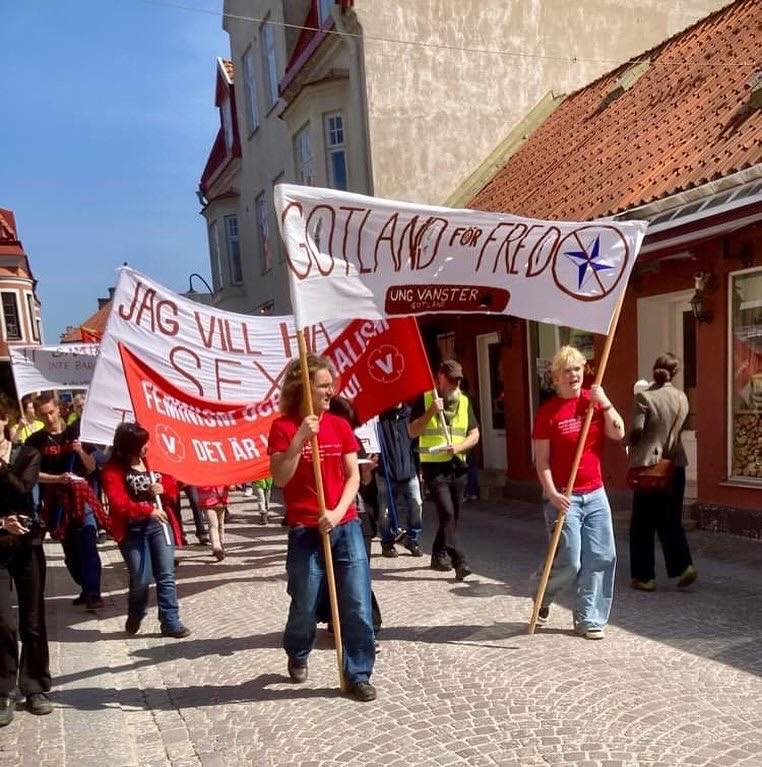 Starten på årets 1 maj-tåg. Främst går två rödklädda personer. Banderolltext: Gotland för fred.